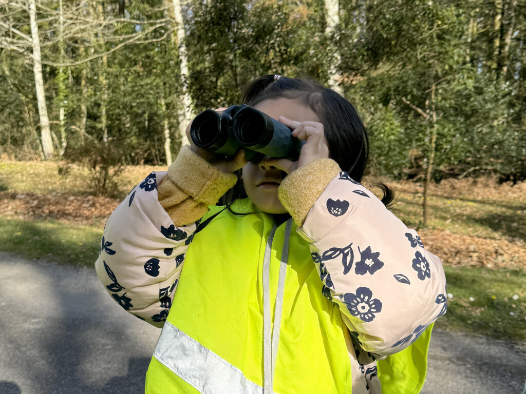 une petite fille regarde la forêt avec des jumelles