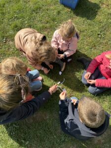 Enfants assis en cercle sur l’herbe qui essaye de réaliser le schéma bilan de l’animation. 